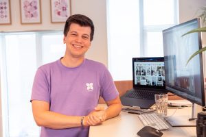 Collega staat lachend voor laptop en bureau