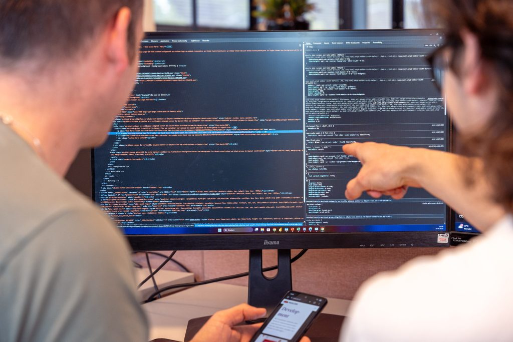 maatwerk software ontwikkelen. Twee medewerkers wijzen naar een scherm