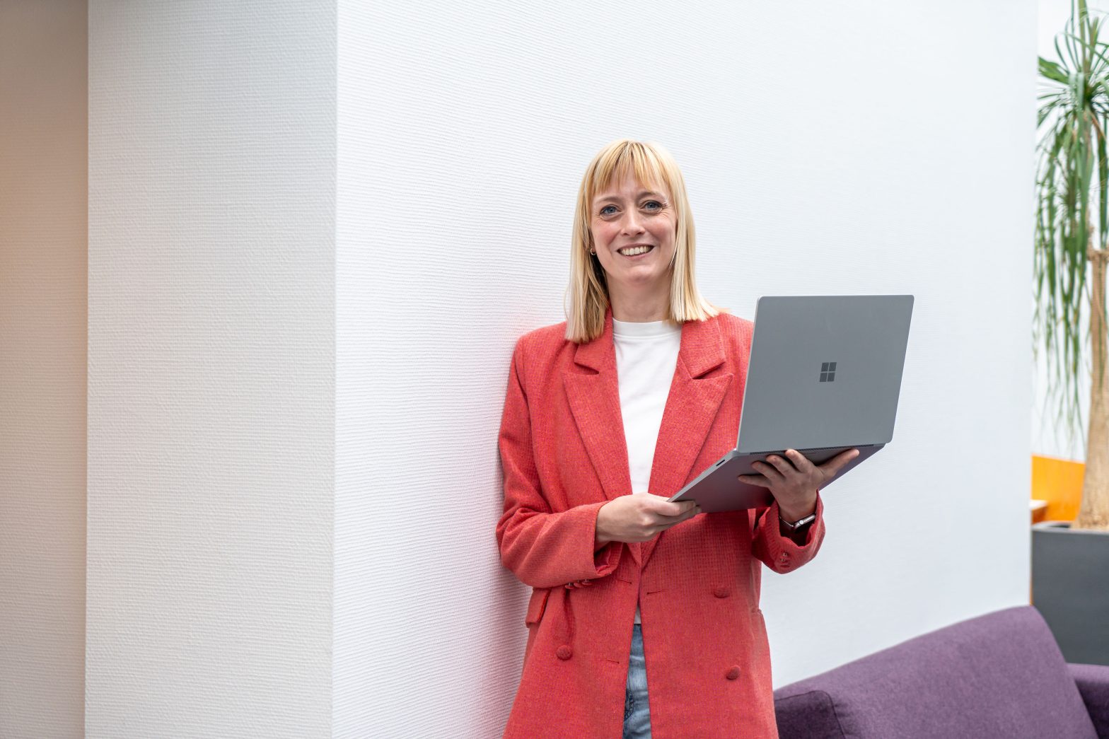 Marketingmedewerker met een laptop, lacht richting de camera