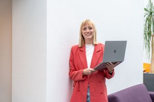 Marketingmedewerker met een laptop, lacht richting de camera